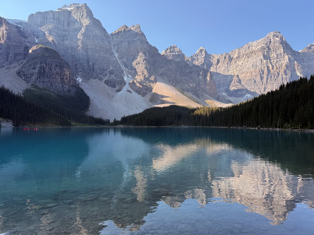 Moraine Lake med skov og stejle bjergtoppe set fra Lakeshore Trail langs søen